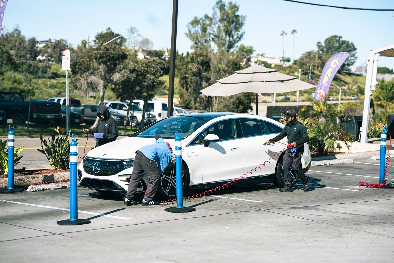 An attendant hand-washing a white Mercedes EQE