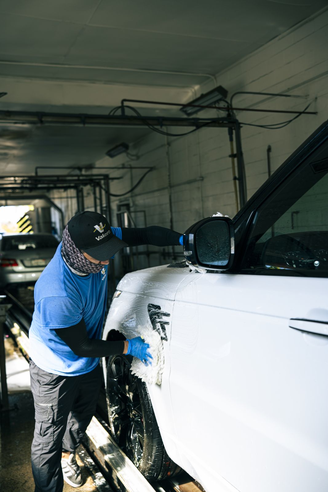 An attendant hand-wiping the panel of a white car