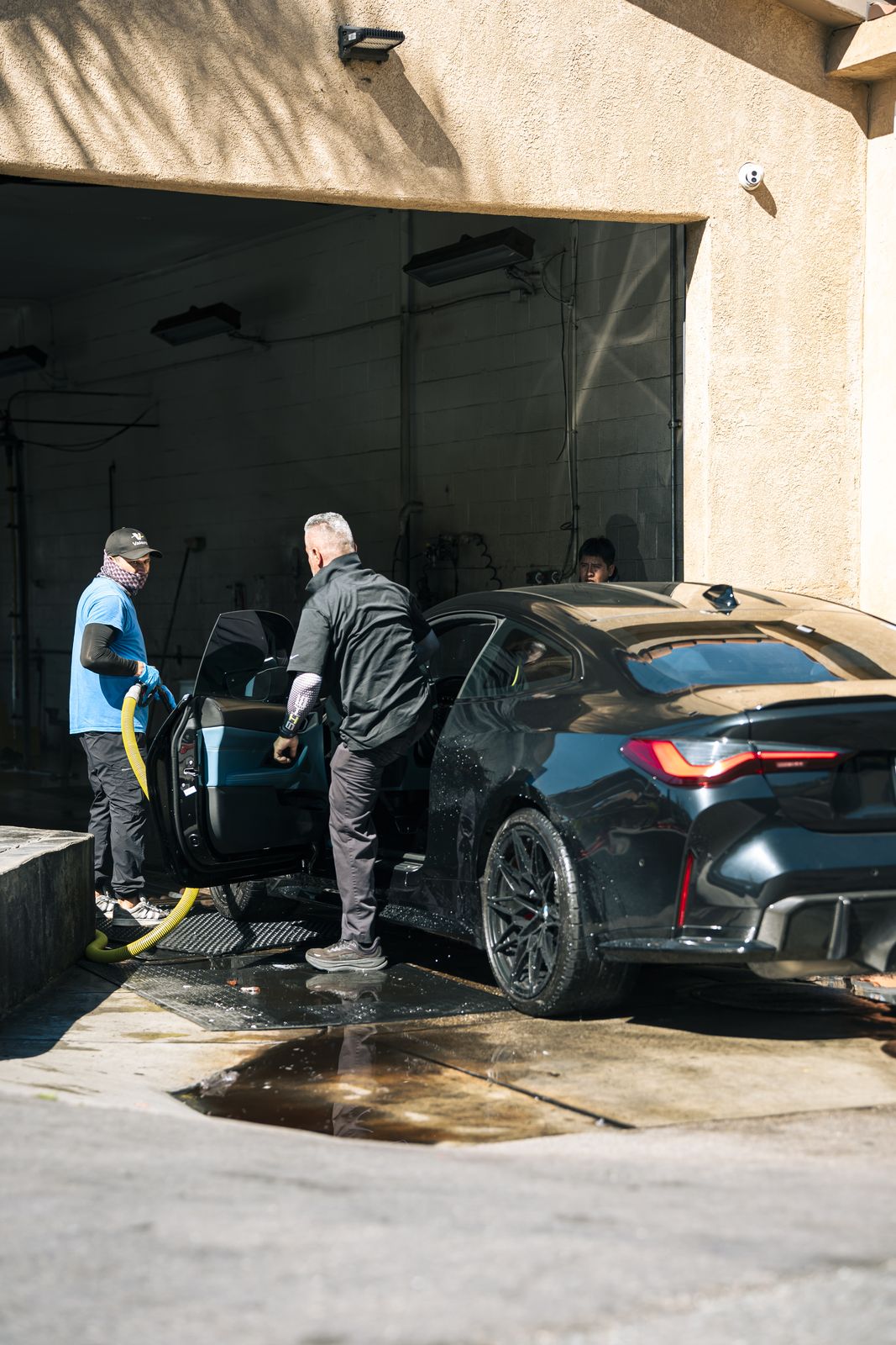 Two attendants hand-washing a BMW M in the wash bay