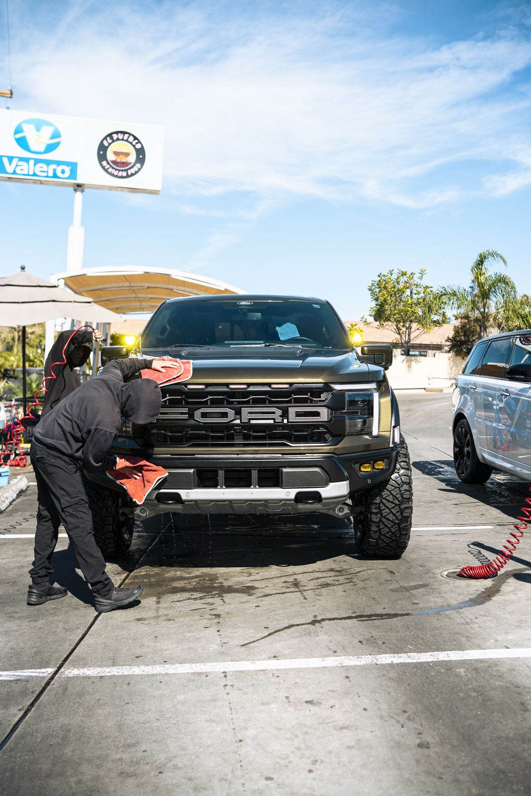 An attendant hand-cleaning the wheel of a Ford Raptor