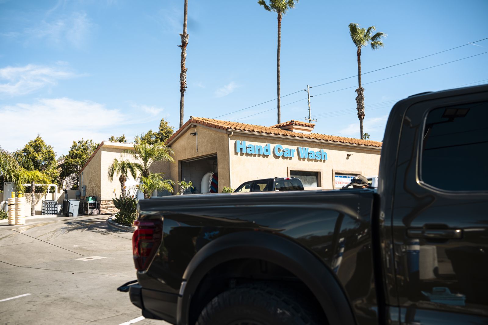 A Ford Raptor bed with the Hand Car Wash storefront behind