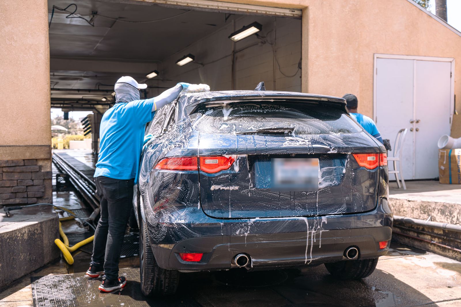 A soaped navy Jaguar F-Pace being hand-washed on the wash pad
