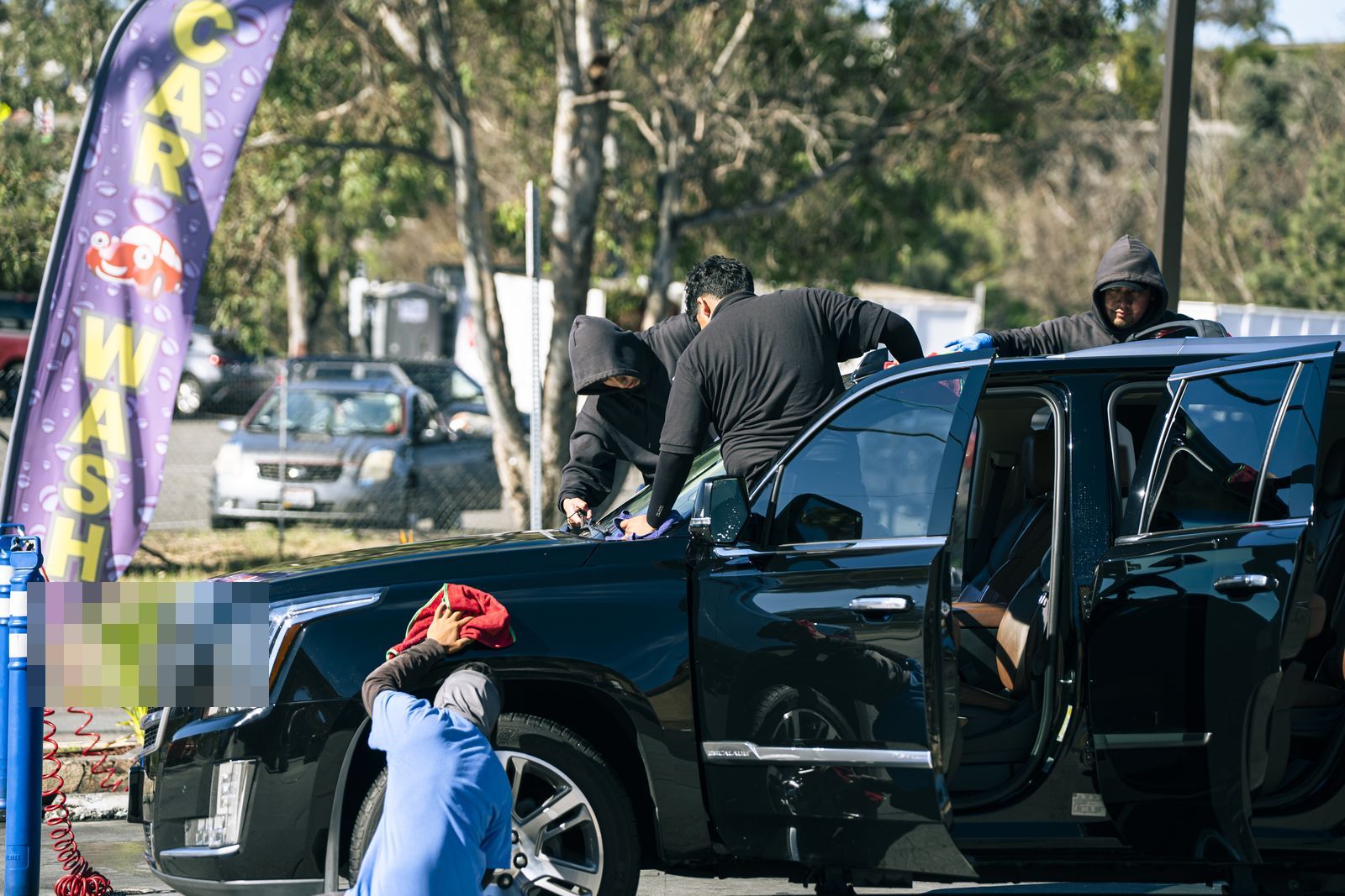A Cadillac Escalade with doors open being detailed